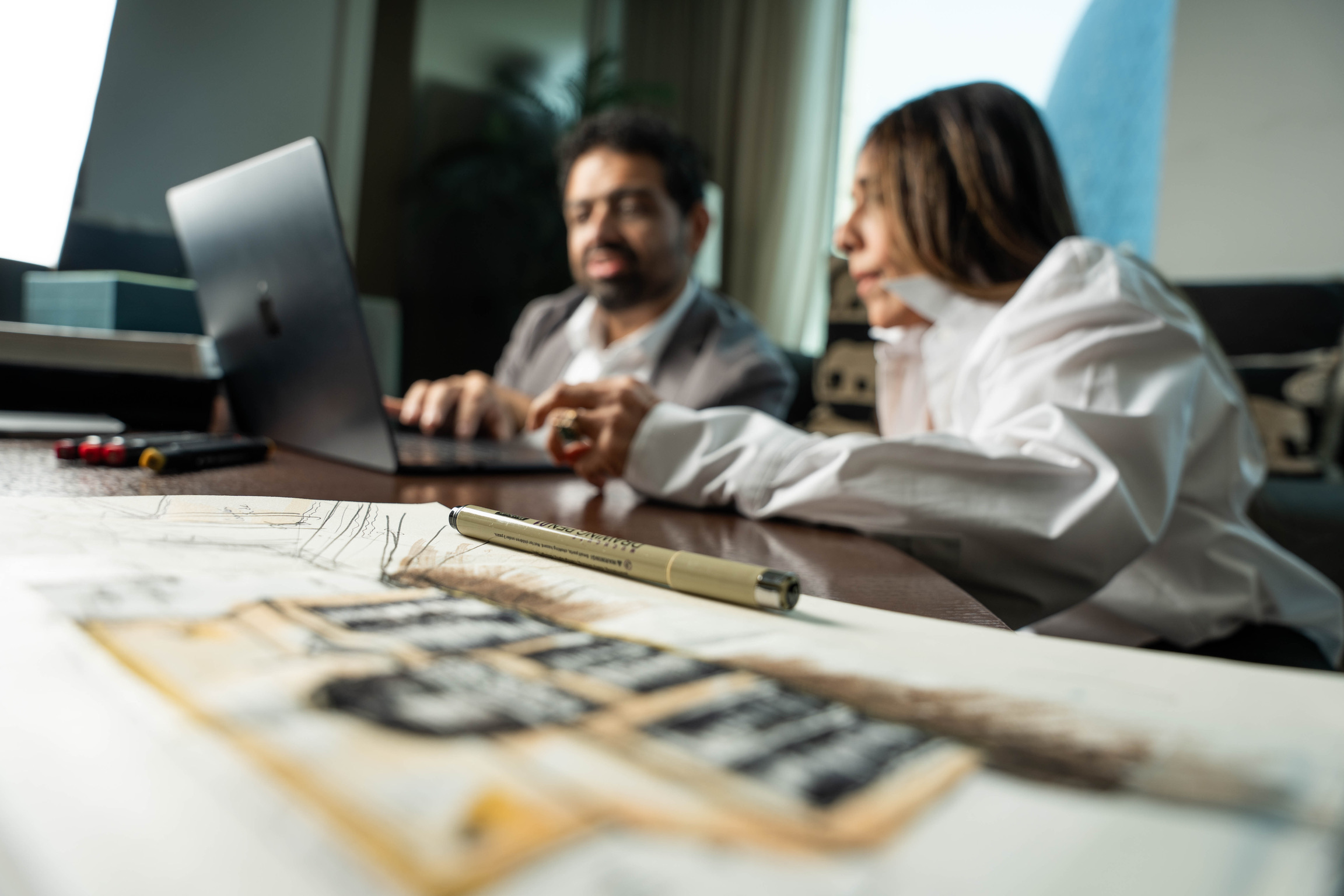 Bushra Khokhar and Tariq Ismail reviewing project records together, schedules and drawings laid out on the desk