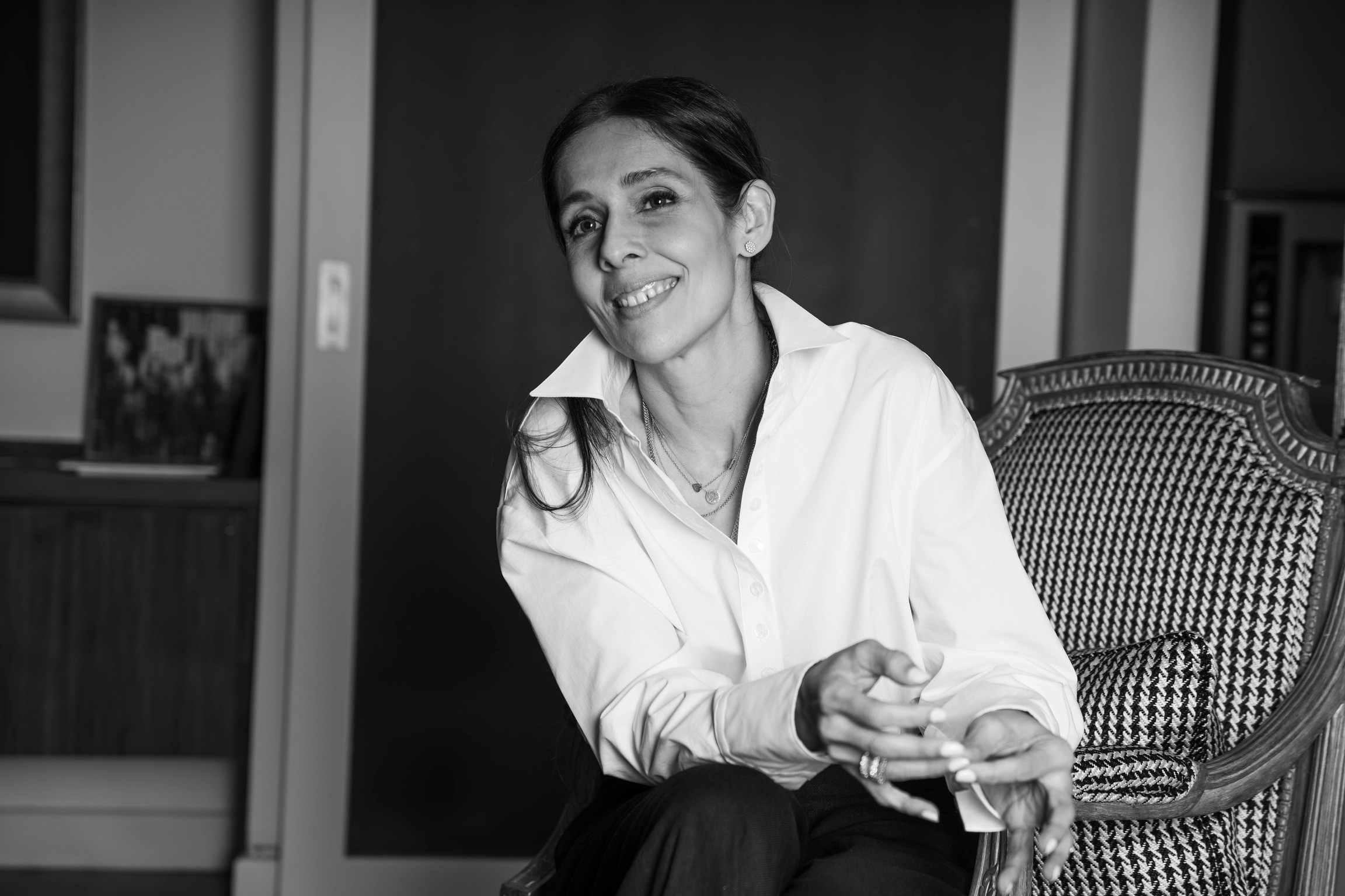 Bushra Khokhar, black and white portrait, seated in a houndstooth armchair